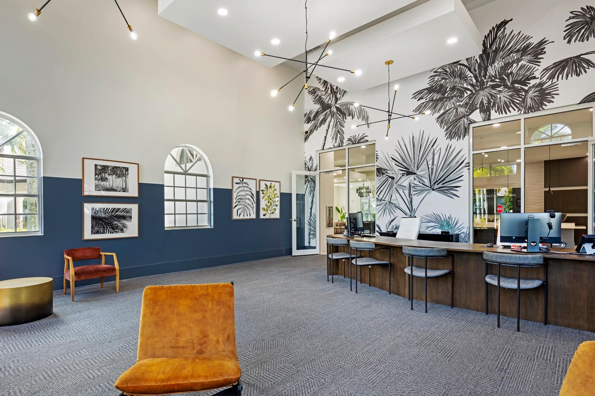 Leasing office employee desks with floral mural on the back wall with waiting area seating