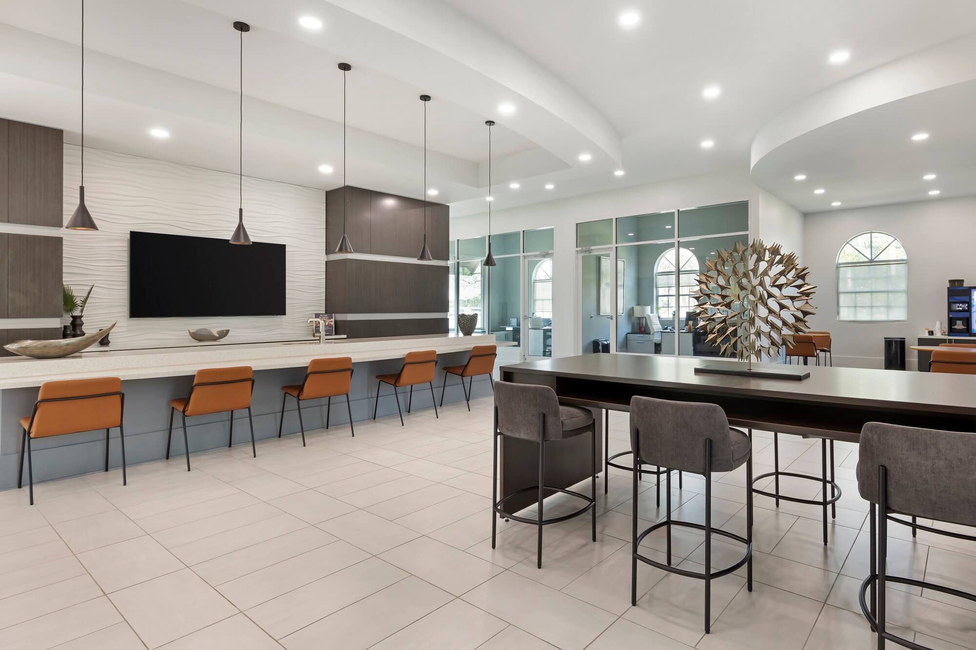 Clubhouse seating area with table and chairs. Kitchen counter seating with tv mounted on the wall