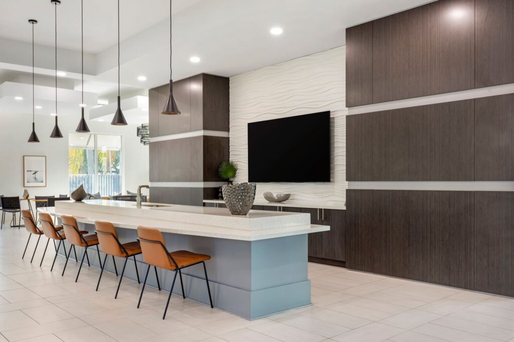 Clubhouse kitchen area with sink and counter seating and tv mounted on the wall