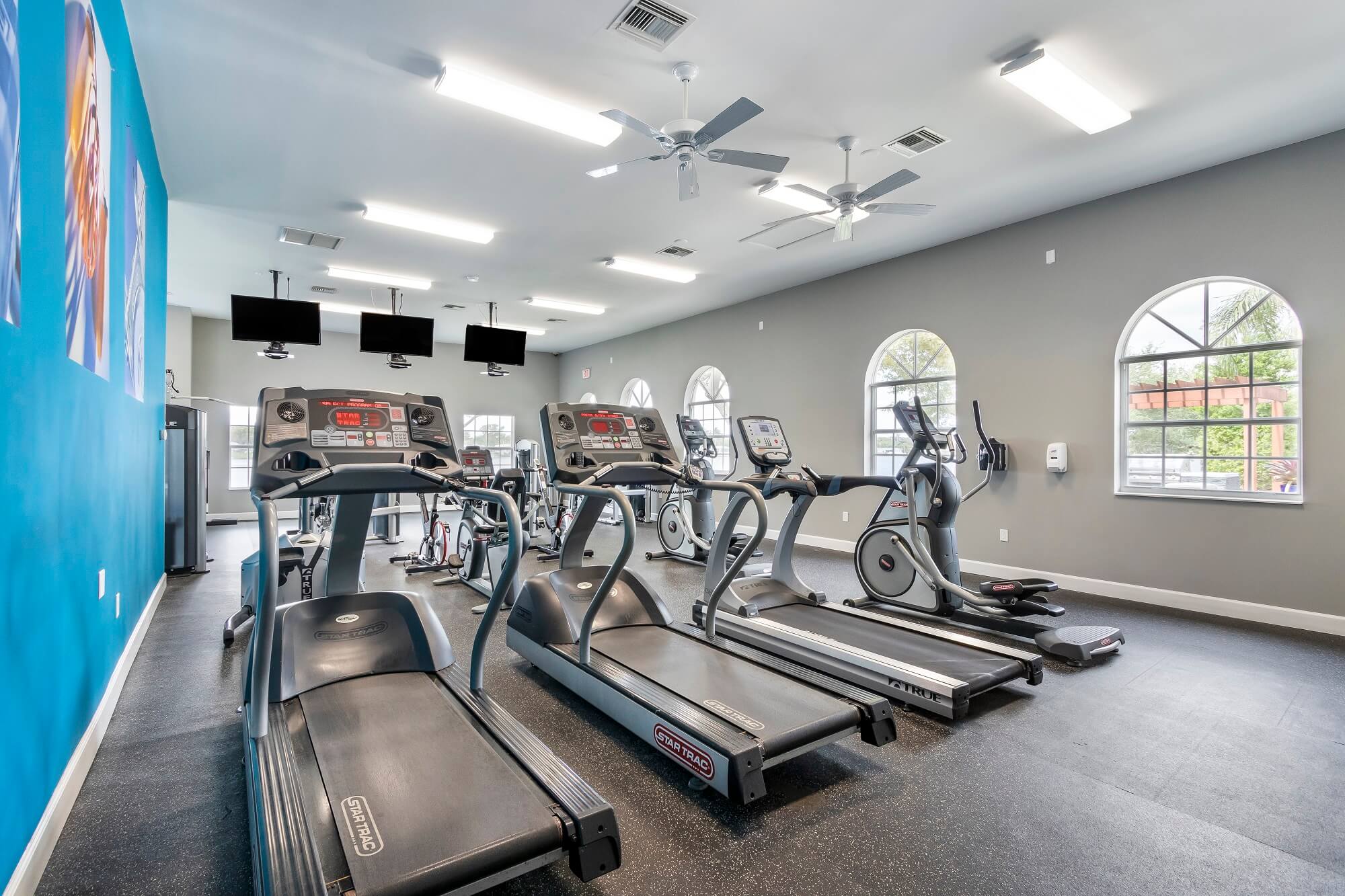 fitness center with cardio training equipment. Tvs hanging from the ceiling