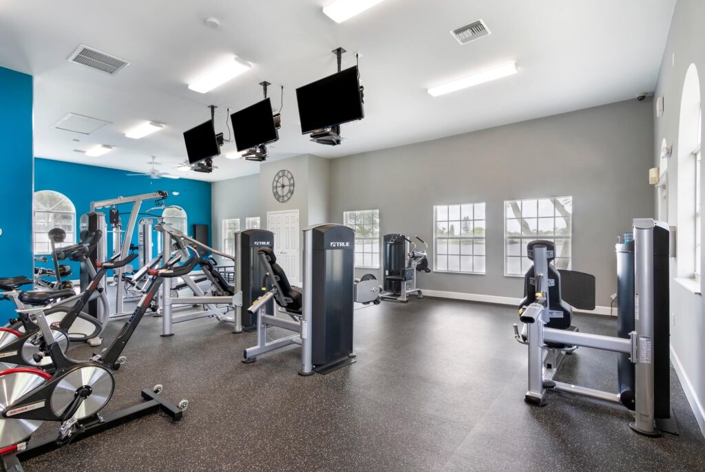 fitness center with cardio and strength training equipment. Tvs hanging from the ceiling