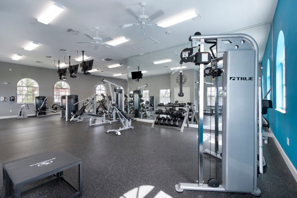 Fitness center with strength training equipment with tvs hanging from the ceiling