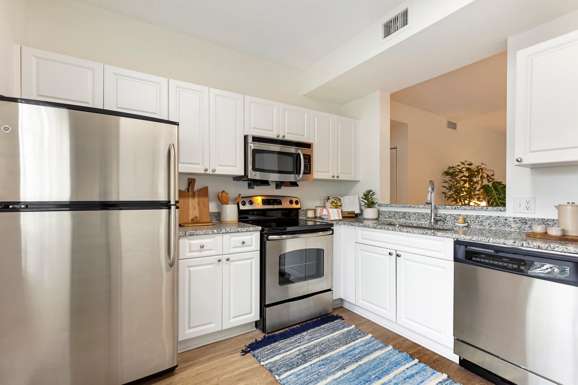 Model apartment kitchen with stainless steel appliances and opening to living room