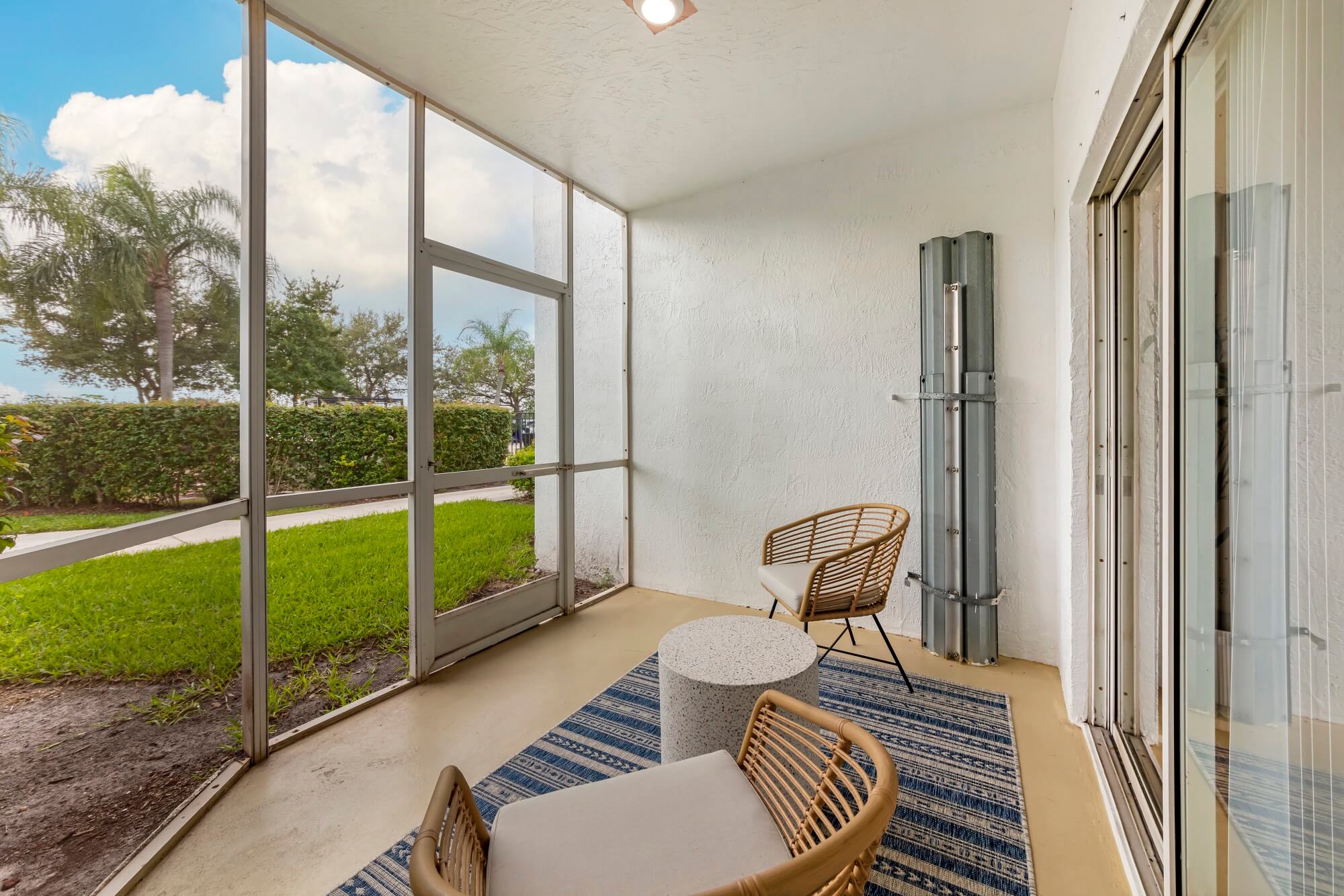 Model unit screened in porch with grassy area outside with palm trees in the back