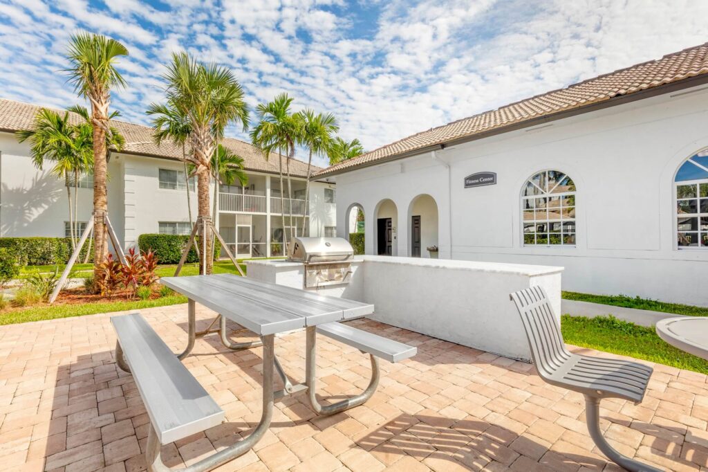Kitchen area out side of fitness area with picnic table and palm trees