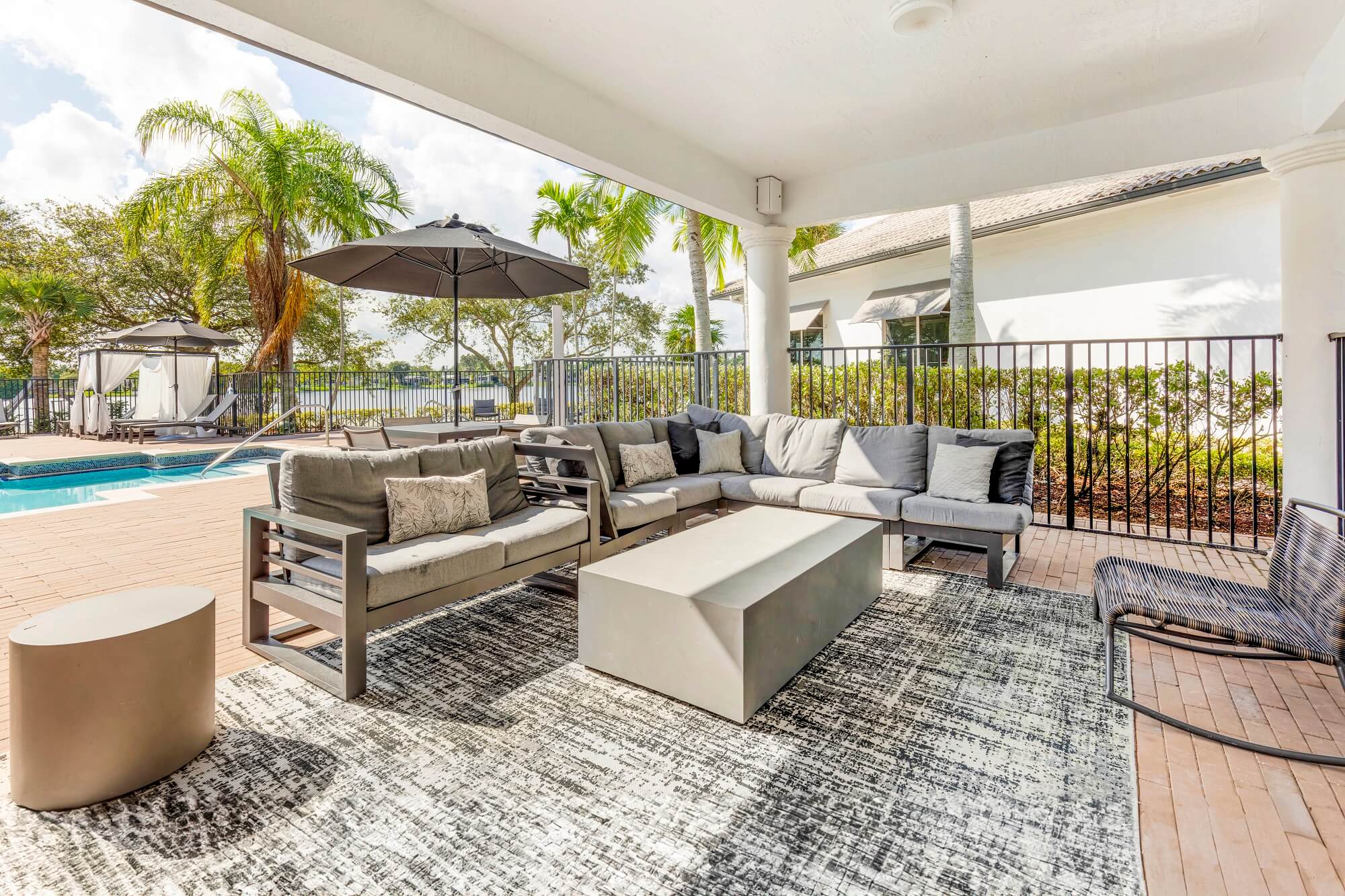 Exterior covered sitting area with sectional couch and side table by the pool